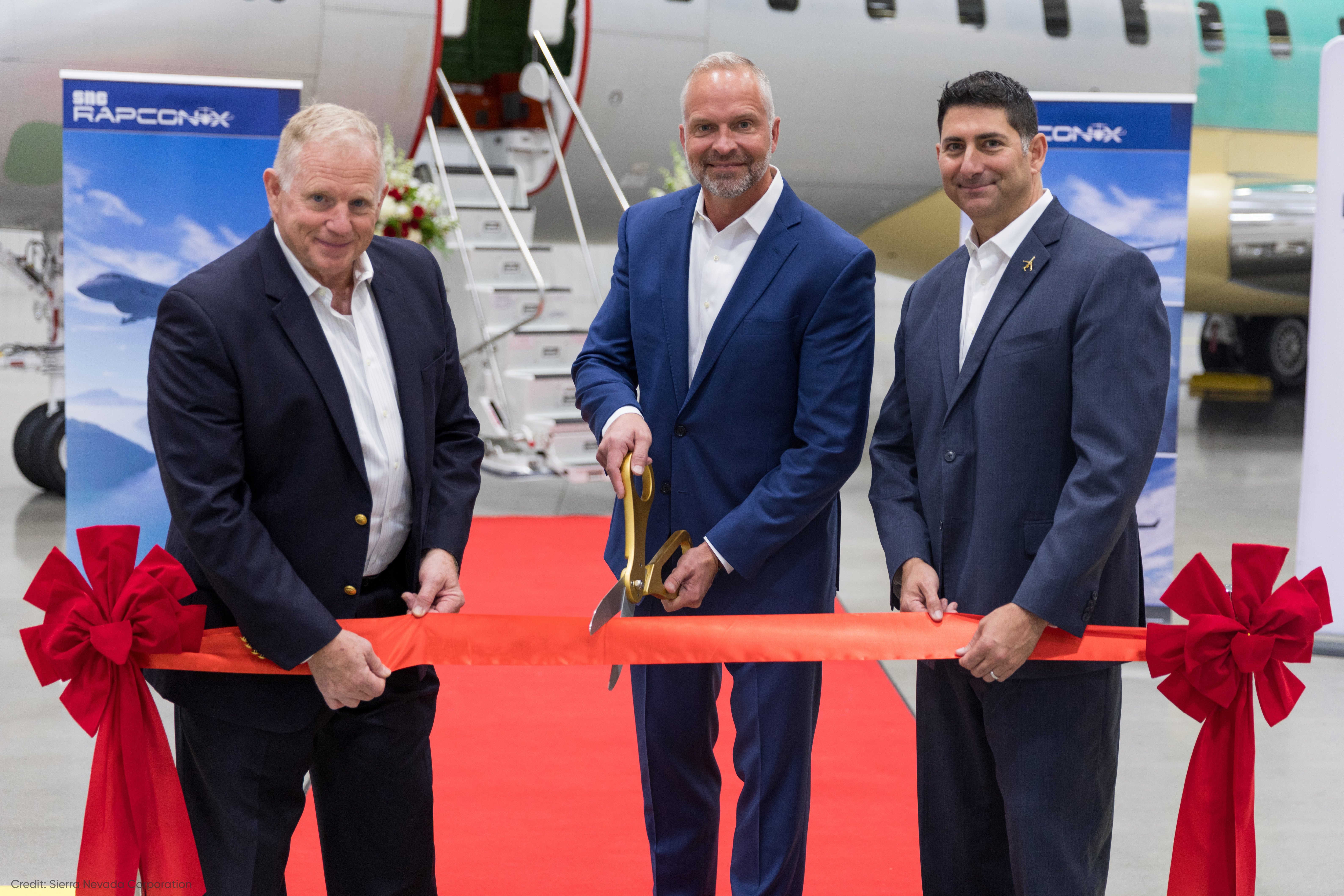 SNC Team Members cut ribbon in front of aircraft